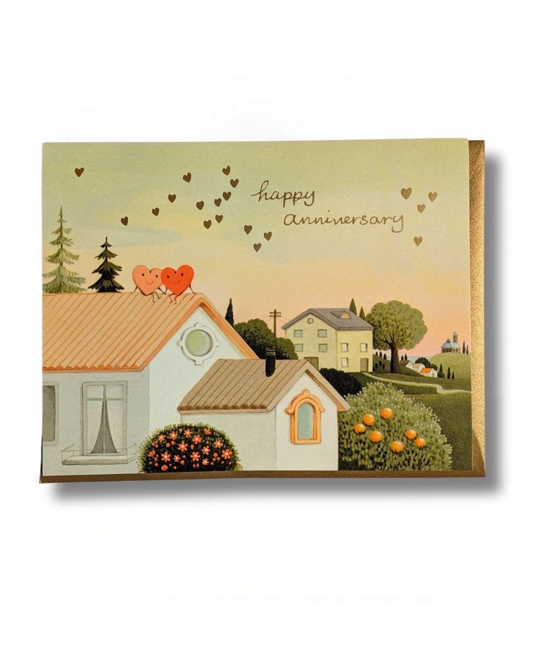 Illustration of a house with hearts on top, surrounded by trees and buildings, with 'Happy Anniversary' text.