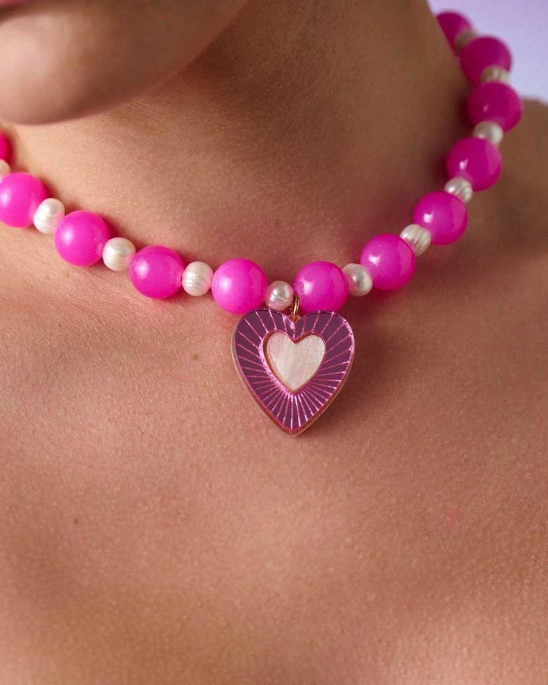 Necklace with pink beads and a heart-shaped charm on a person's neck