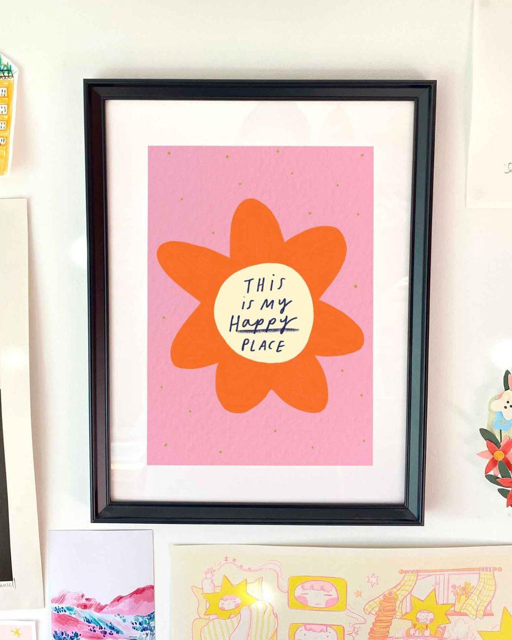Framed artwork with a flower design and 'This is my happy place' text on a pink background.