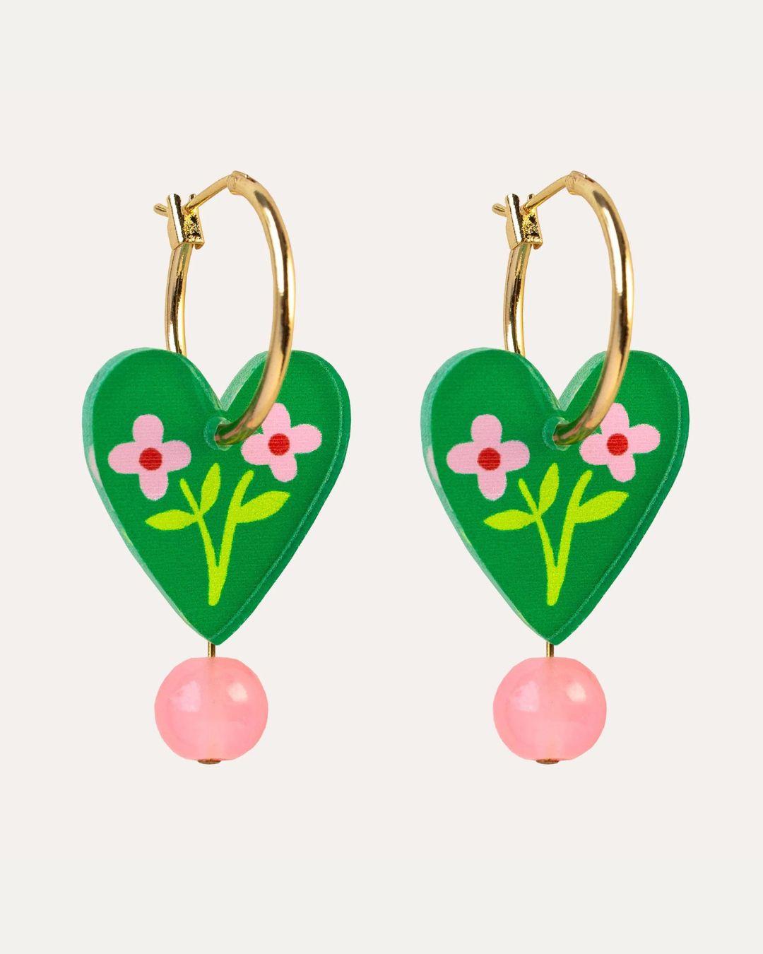 Heart-shaped earrings with floral designs and pink beads on a white background