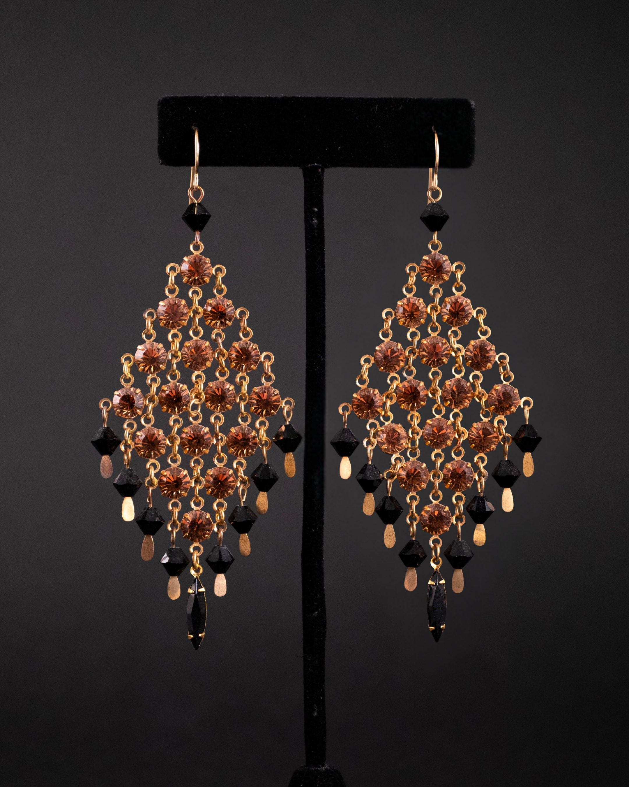 Pair of chandelier earrings with amber and black Swarovksi scrystals on a dark background