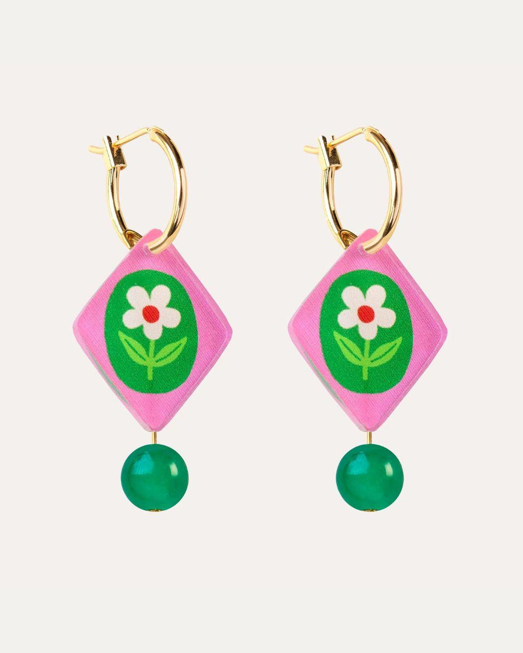 Pair of earrings with pink diamond charms featuring a white flower design, green glass beads, and gold hoop components on a white background.