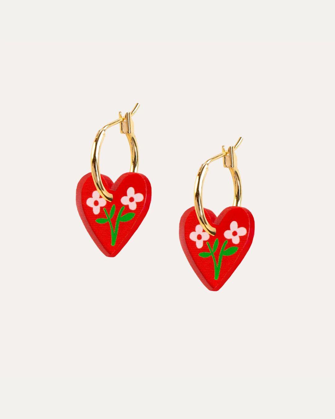 Pair of red and gold heart hoop earrings with flowers on a white background