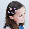 Girl with colorful hair clips in her hair against a plain background