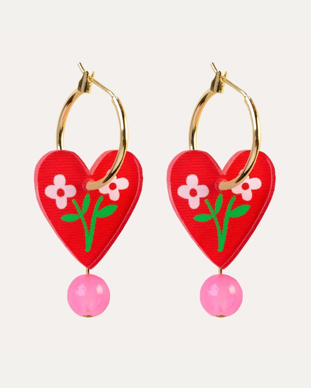 Heart-shaped earrings with floral design and pink beads on a white background