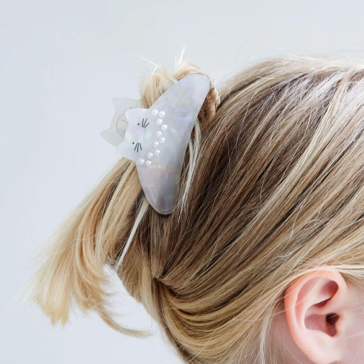 Hair clip with cat design on a person's hair against a white background