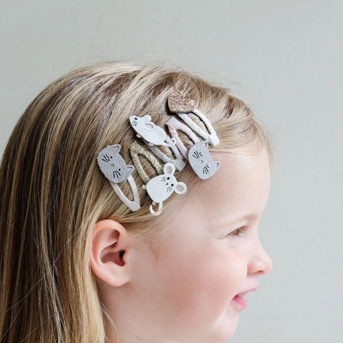 Child with decorative hair clips on a plain background