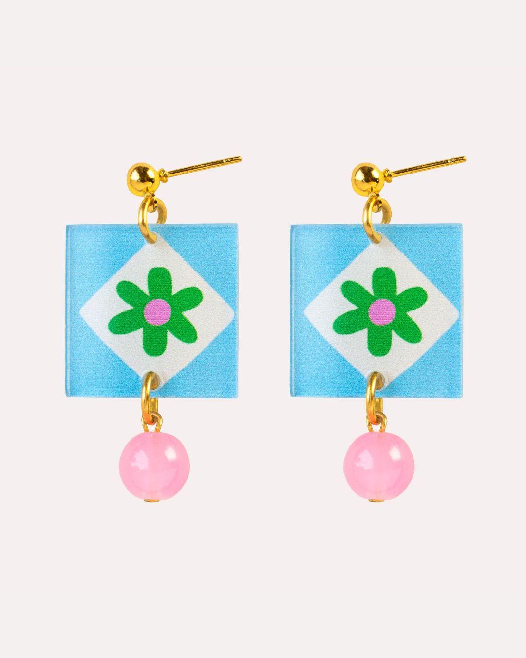 Pair of earrings with floral design and pink beads on a light blue background