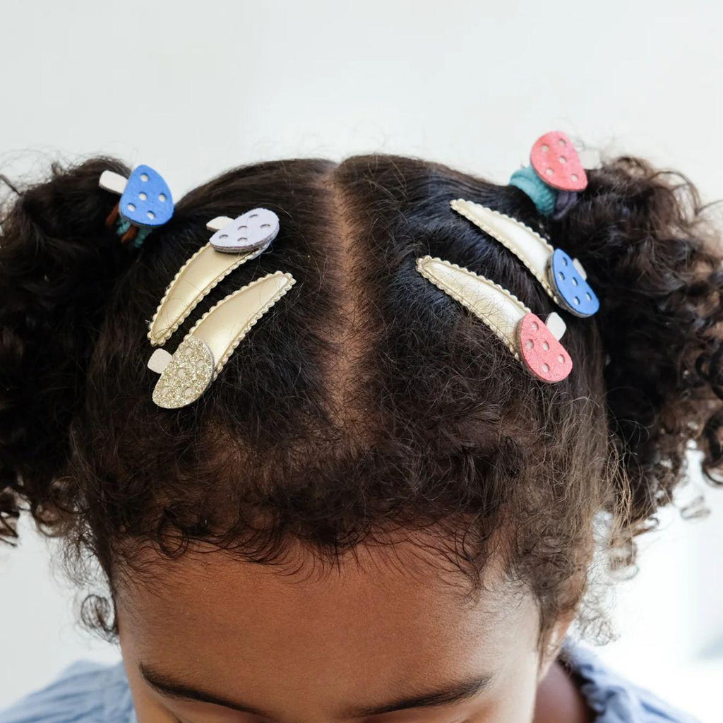 Child's hair with colorful hair clips on a light background