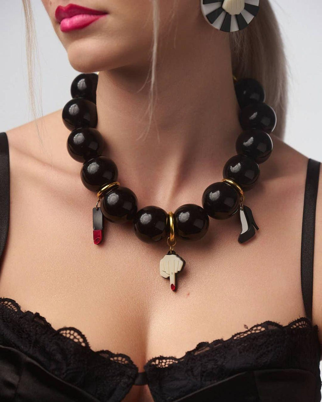 Black beaded necklace with charms worn by a model against a neutral background