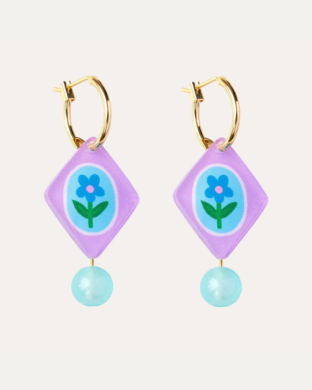 Pair of hoop earrings with purple diamond-shaped charms featuring a blue flower design on a white background.