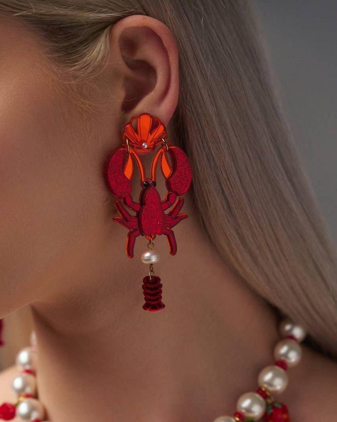Red lobster-shaped earring worn by a person with a blurred background