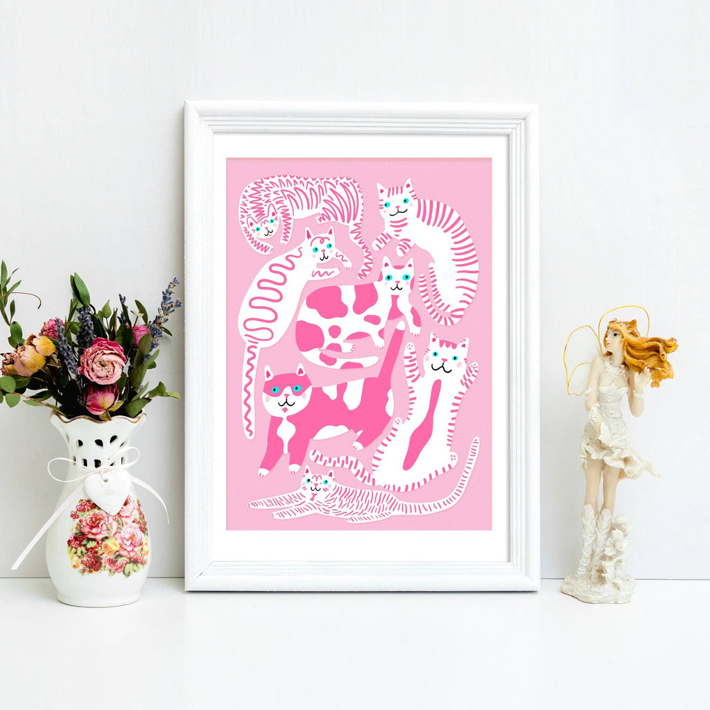 Framed pink art print with white animal illustrations on a white surface with decorative items.
