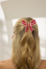 Blonde hair with a red and white striped bow against a neutral background