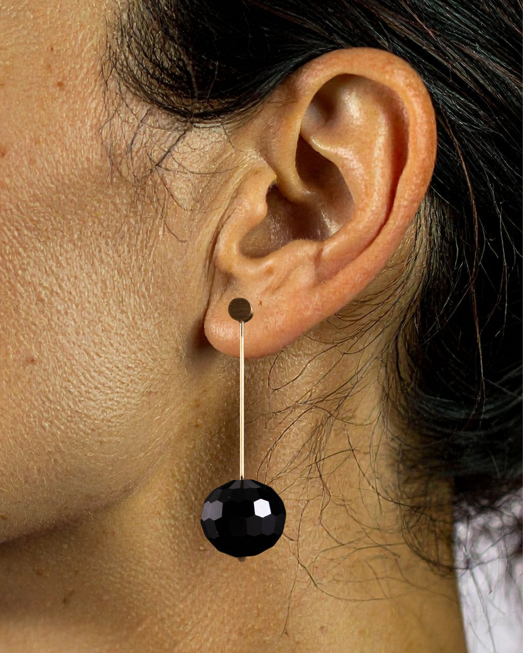 Close-up of an ear wearing a black dangling earring.