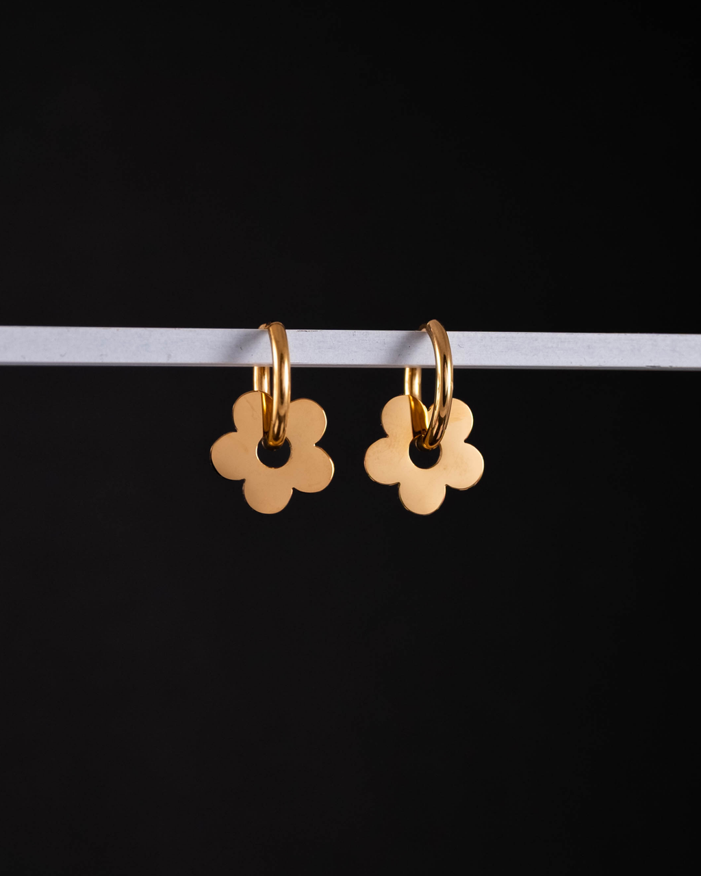 Gold flower-shaped earrings on a black background