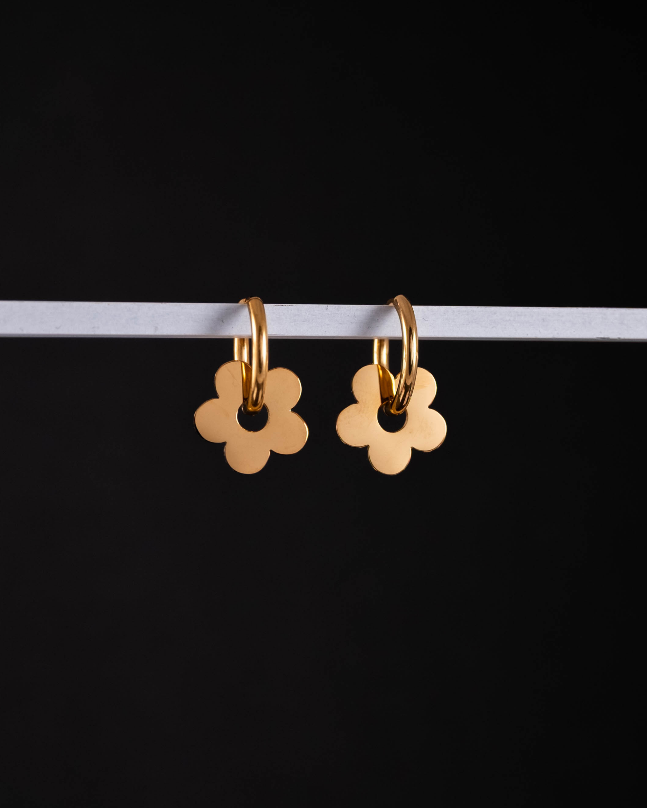 Gold flower-shaped earrings on a black background