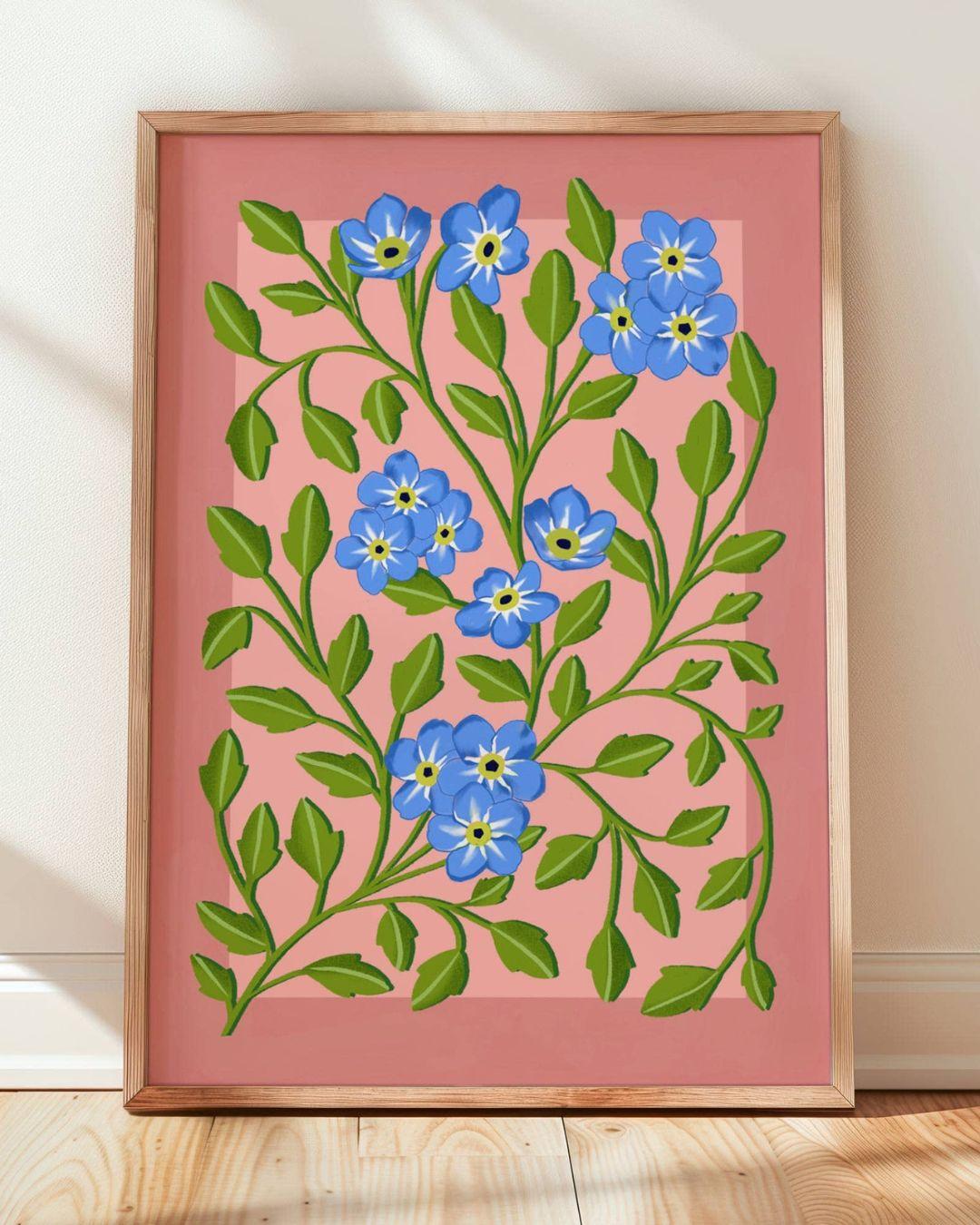 Framed artwork with blue flowers and green leaves on a pink background
