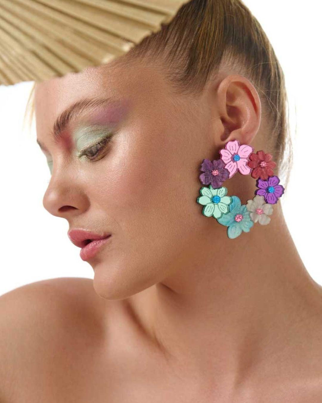 Close-up of a person wearing colourful floral hoop earrings with a neutral background