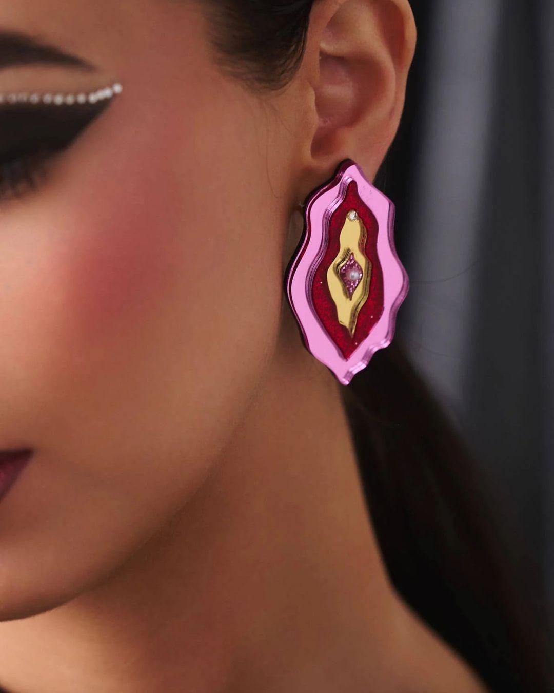 Close-up of a person wearing a pink and gold earring.