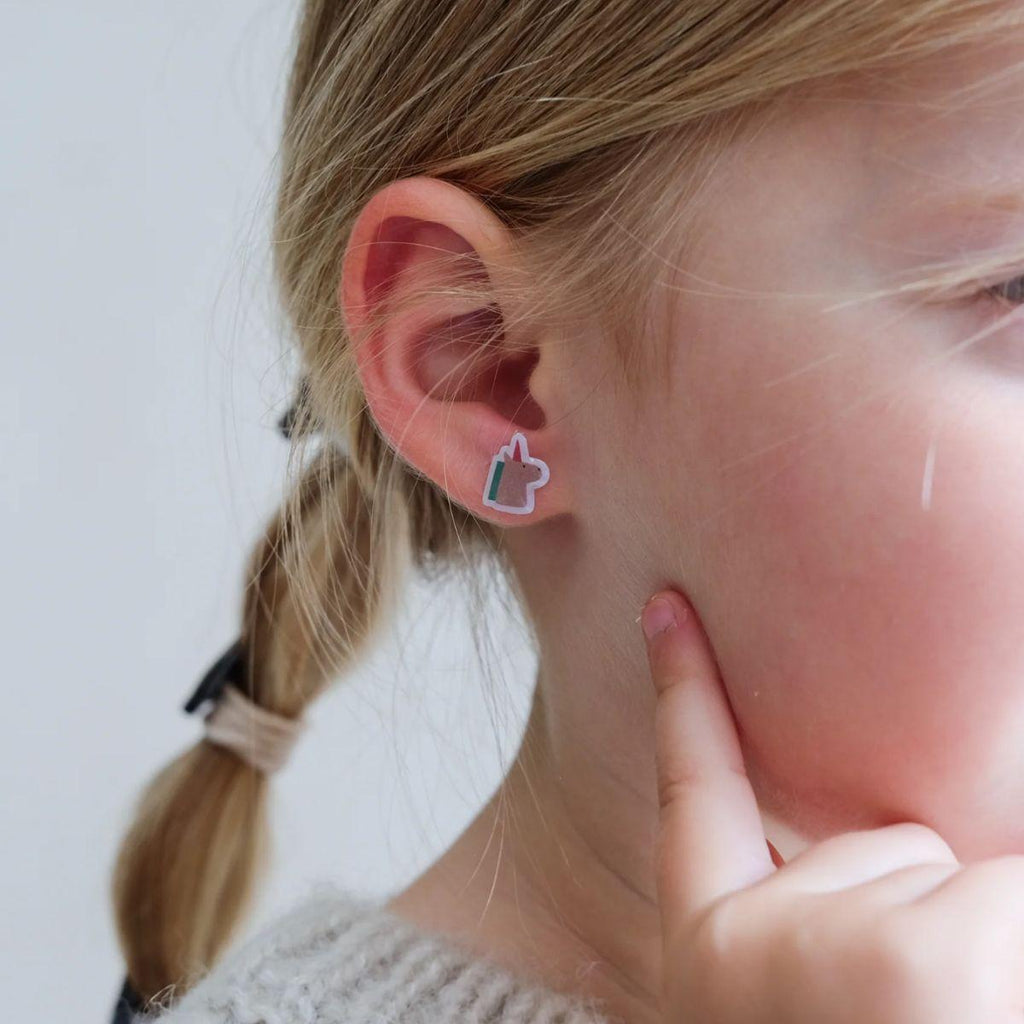 Close-up of a person wearing a heart-shaped earring with a small black detail.