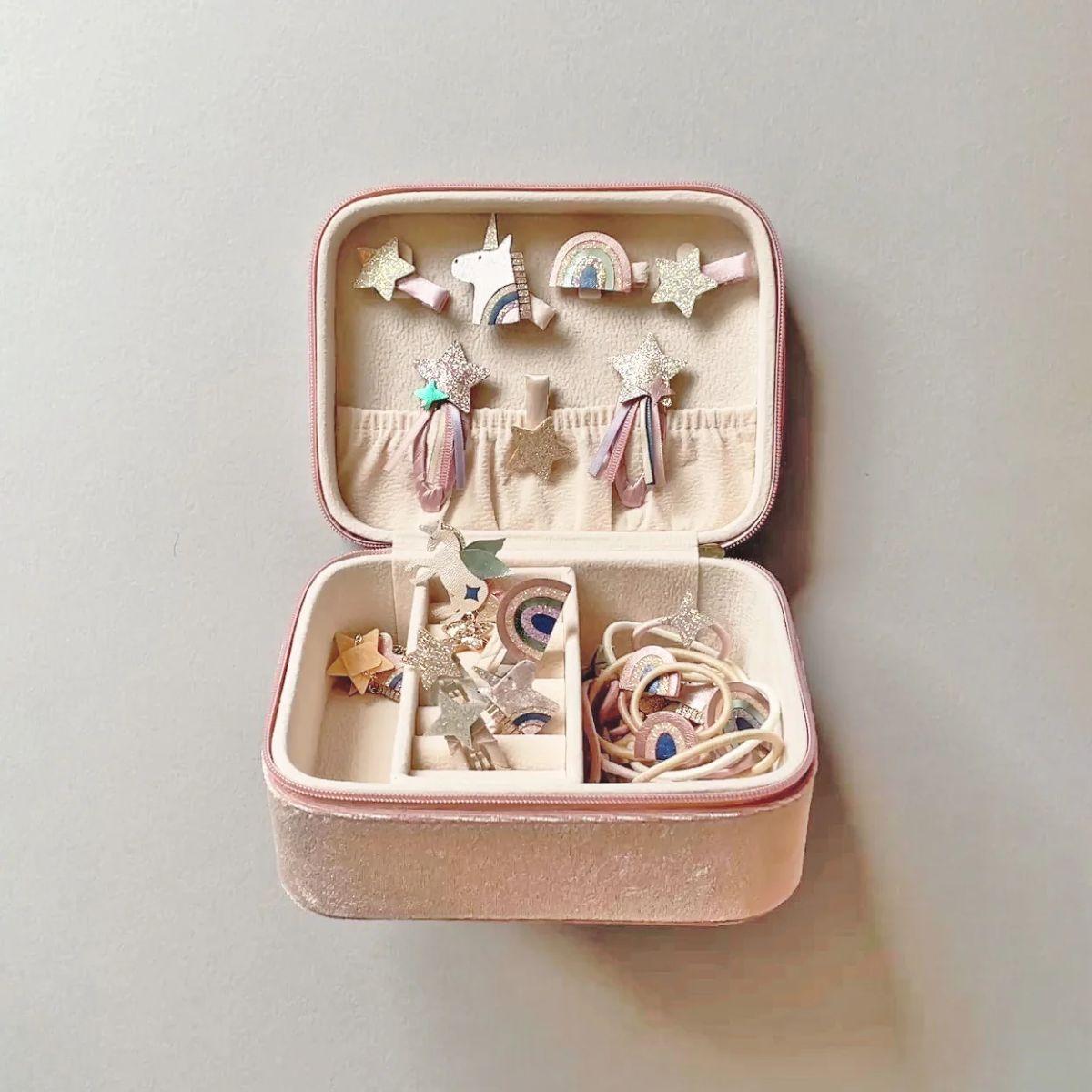Pink jewelry case with decorative items on a light gray background