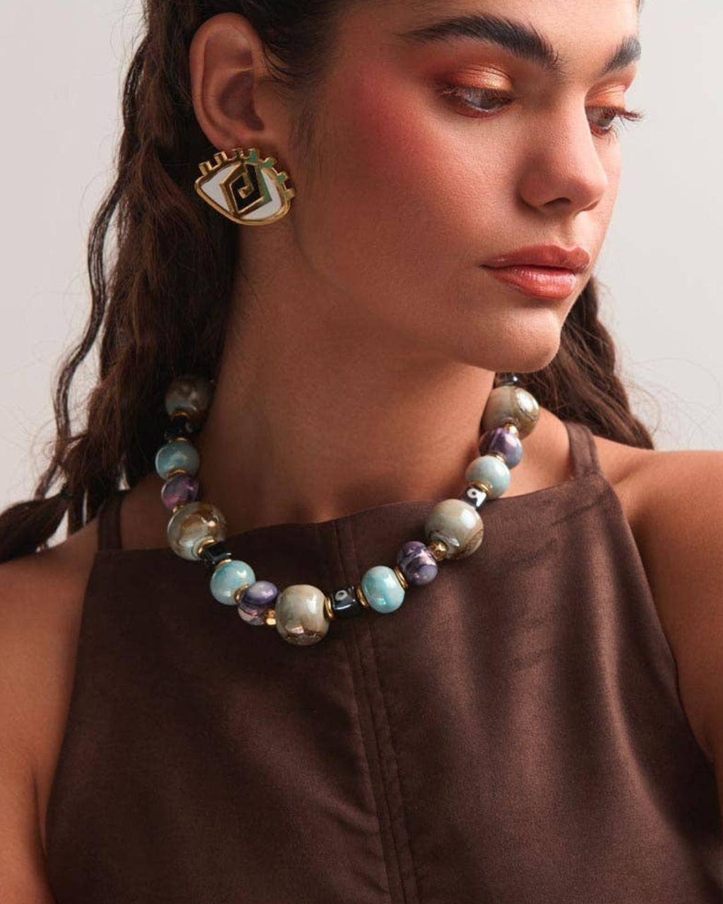 Person wearing a beaded necklace and earrings against a neutral background