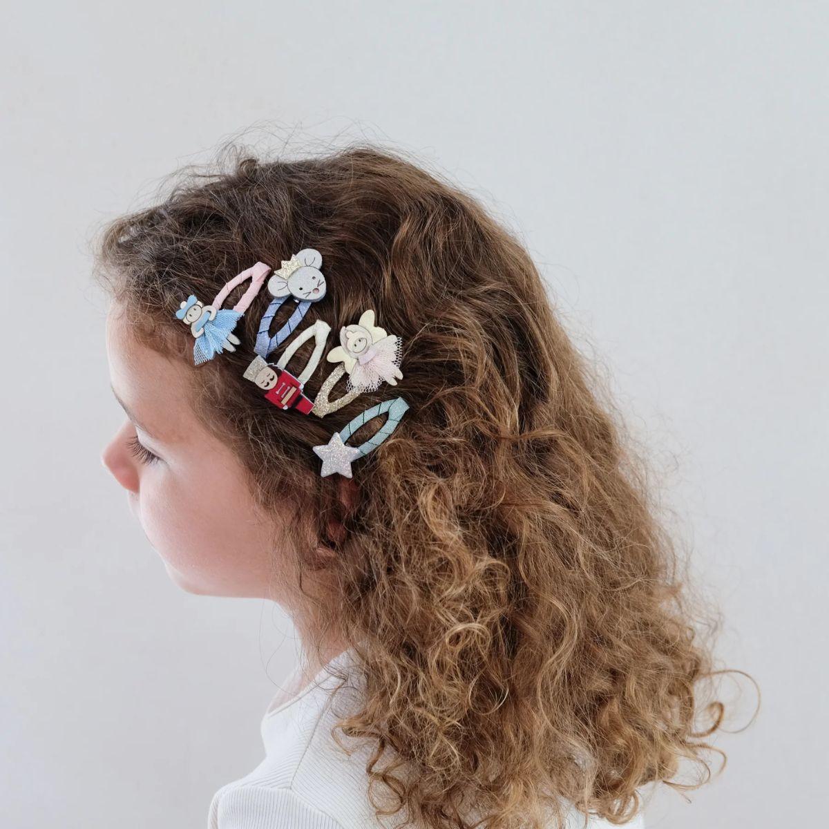 Child with colorful hair clips on a plain background
