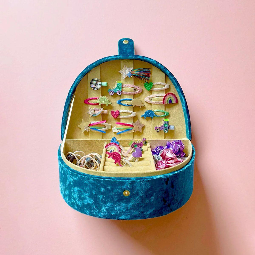 Blue jewelry box with colorful hair clips on a pink background