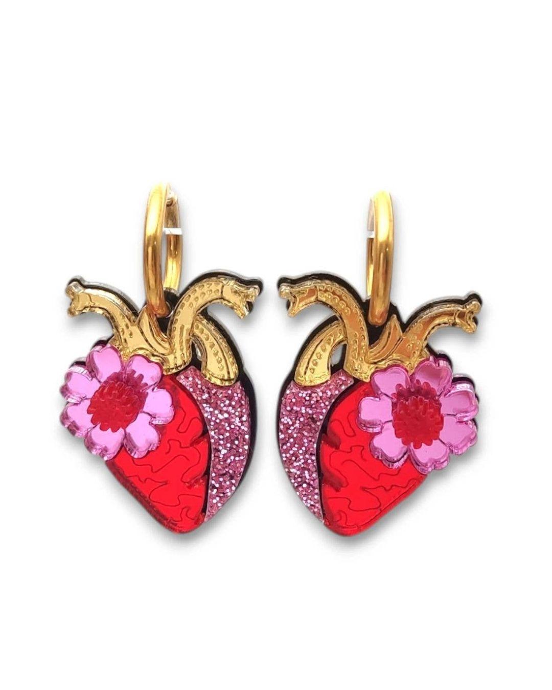 Heart-shaped earrings with pink flowers and gold accents on a white background