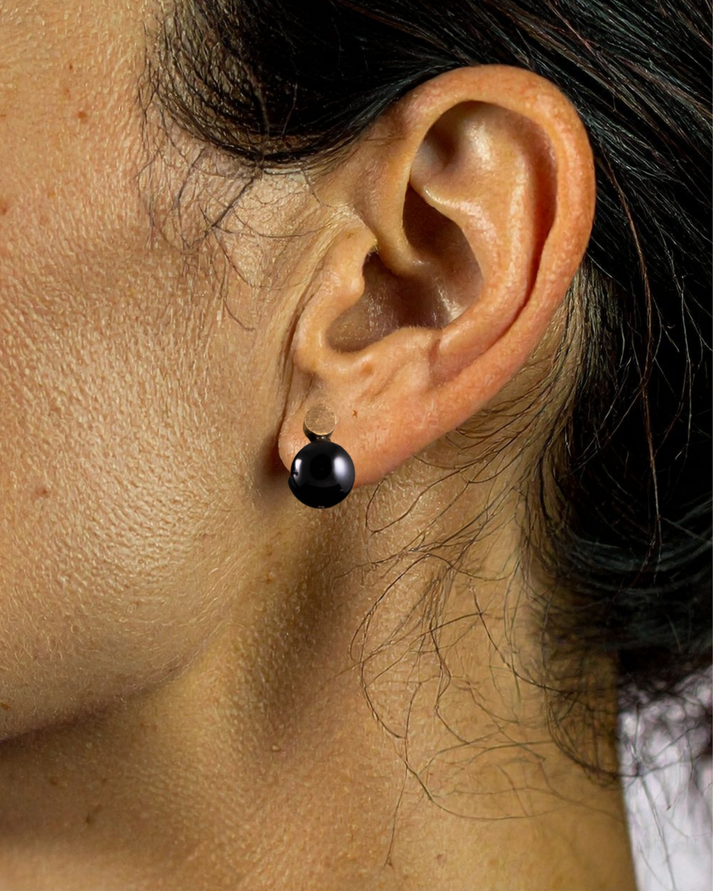 Close-up of an ear wearing a black earring with a blurred background