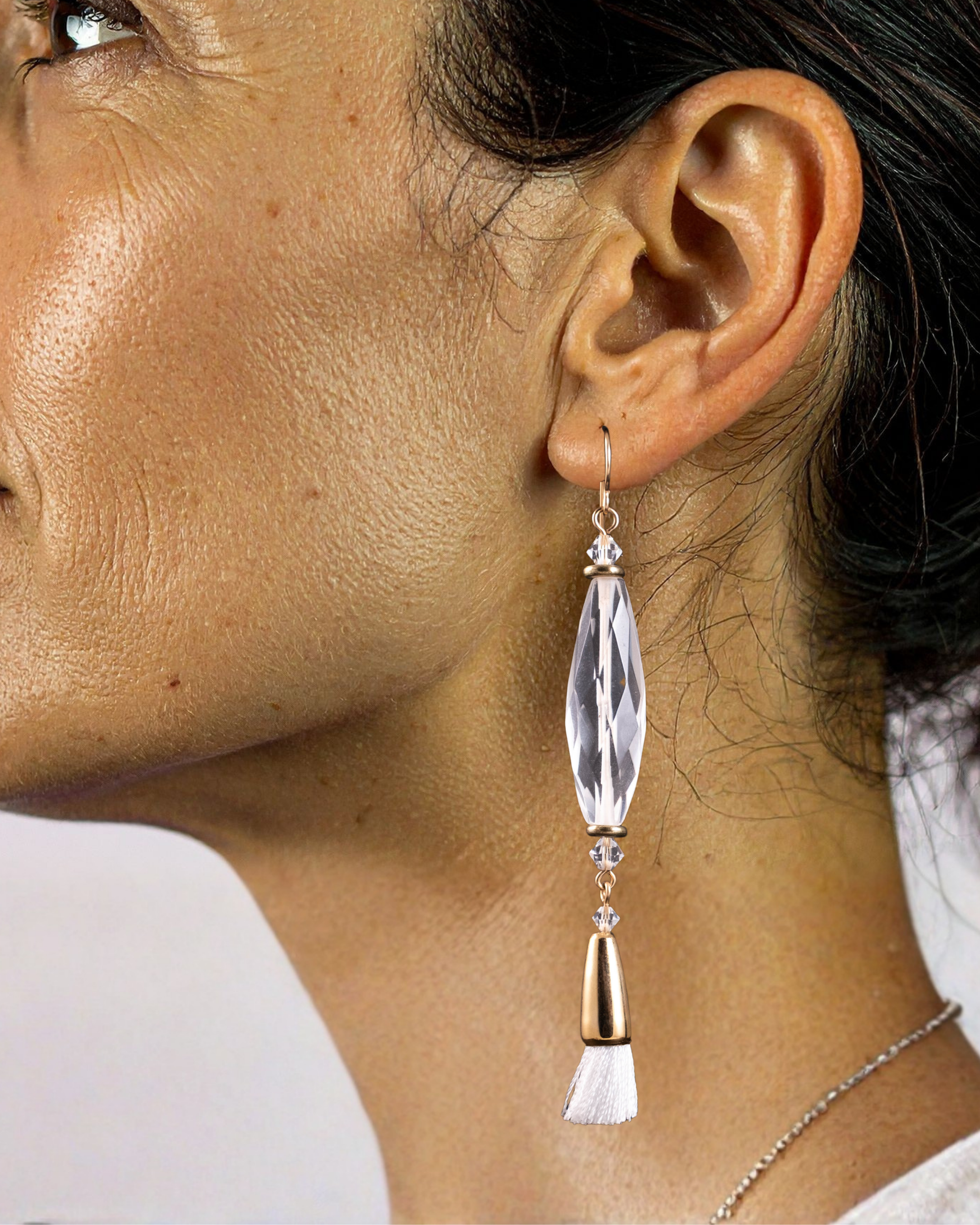Close-up of a woman wearing a dangling earring with a clear quartz and gold accent.