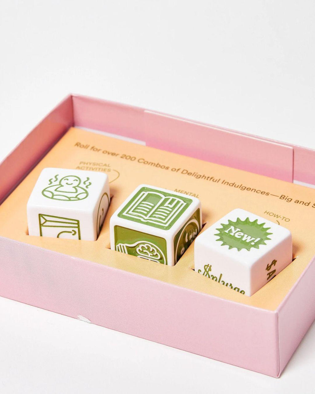 Three dice with green designs in a pink box