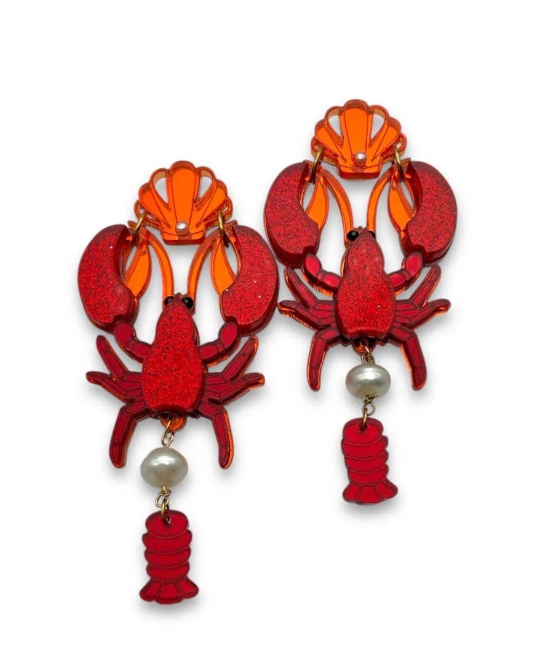 Red and orange lobster-shaped earrings with pearl accents on a white background