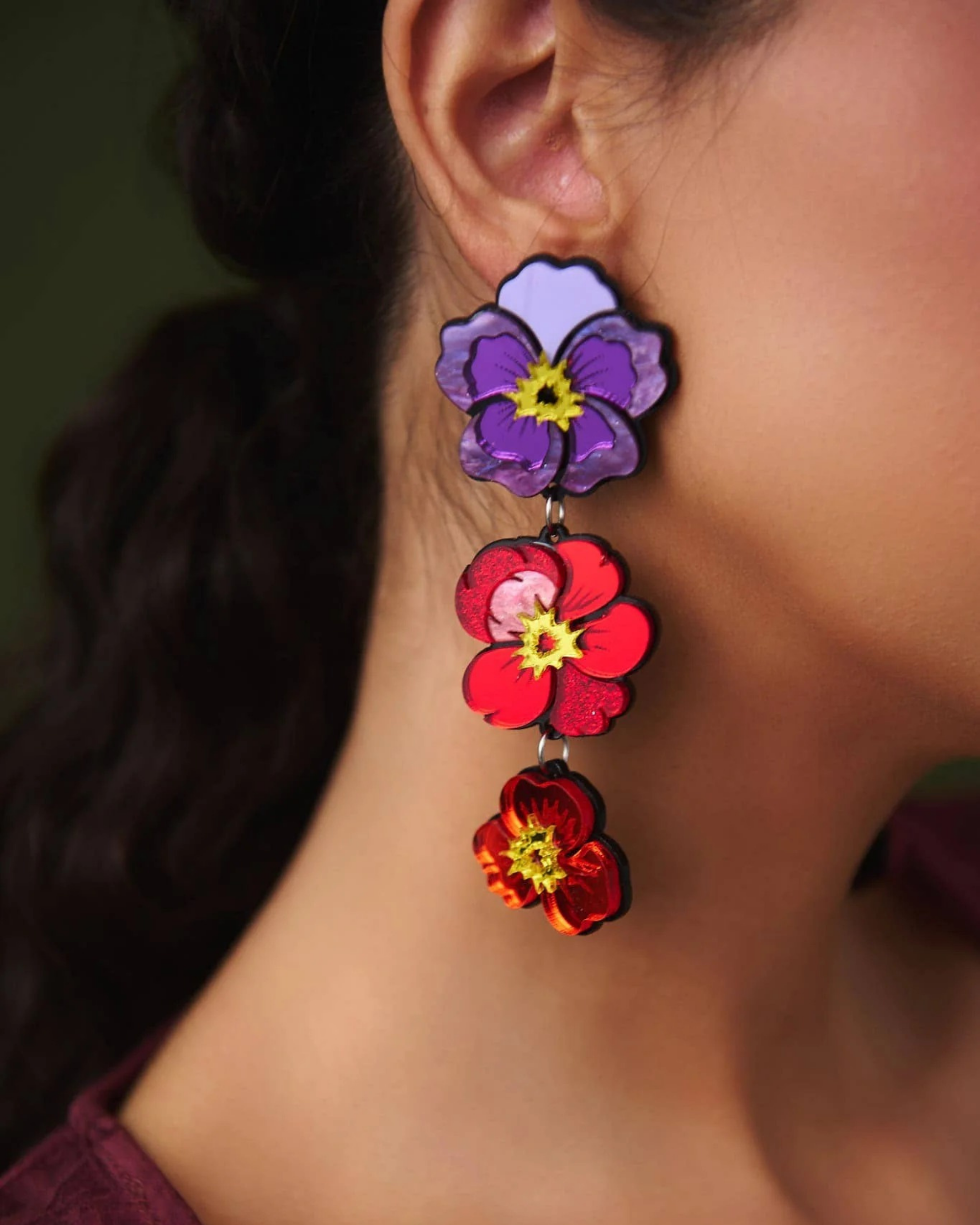 Close-up of colorful flower-shaped earrings worn by a person.