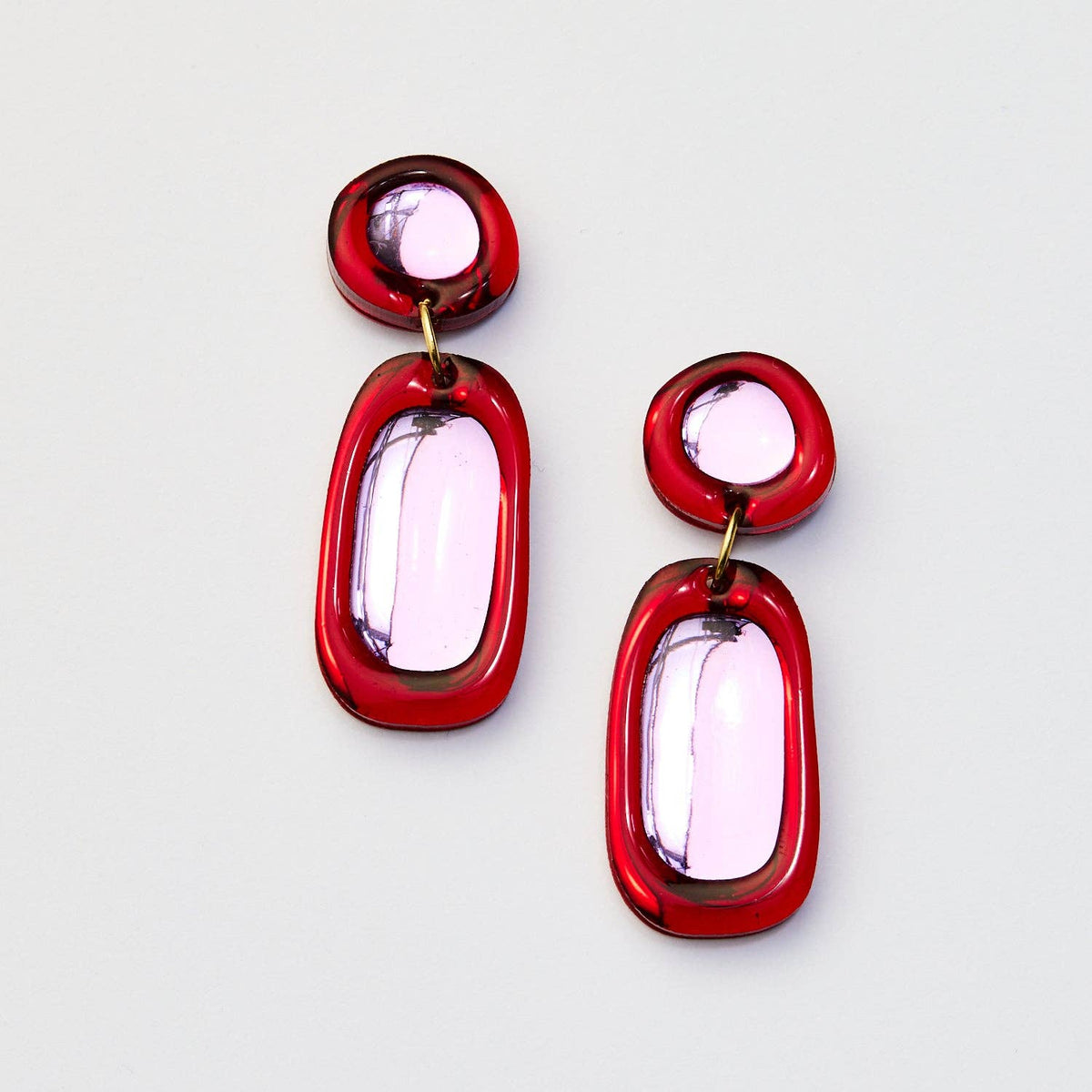 Red and pink earrings on a light gray background
