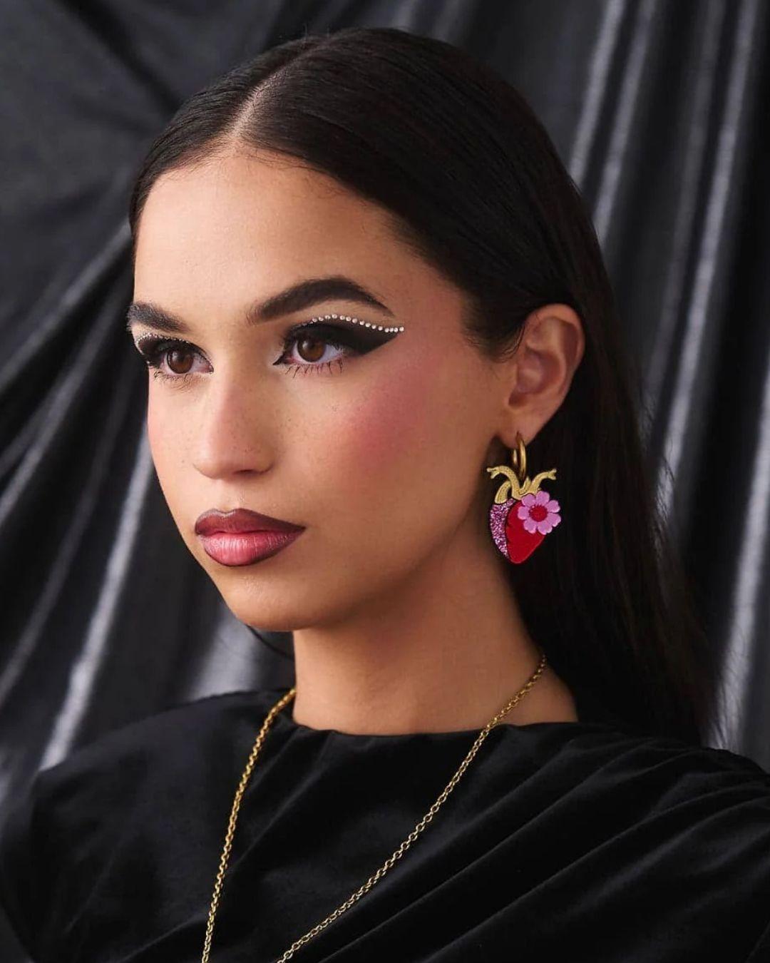 Close-up of a person wearing anatomical heart earring against a black background