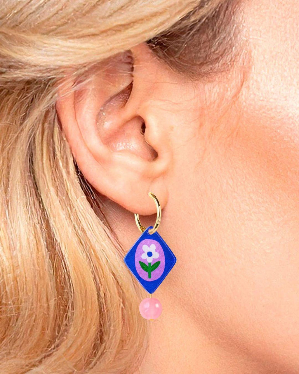 Close-up of an ear wearing a colorful earring with a flower design.