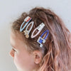 Child with colorful hair clips in their hair against a plain background