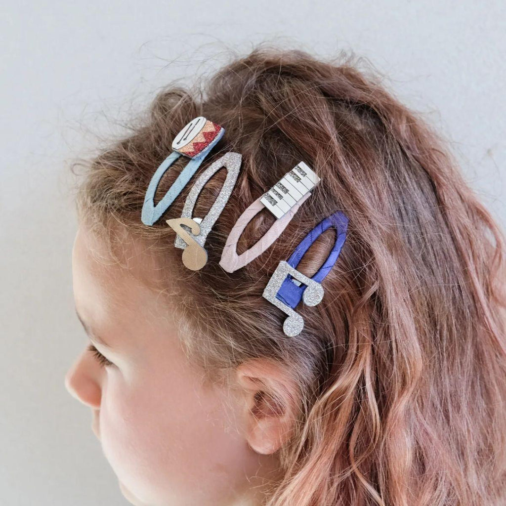 Child with colorful hair clips in their hair against a plain background