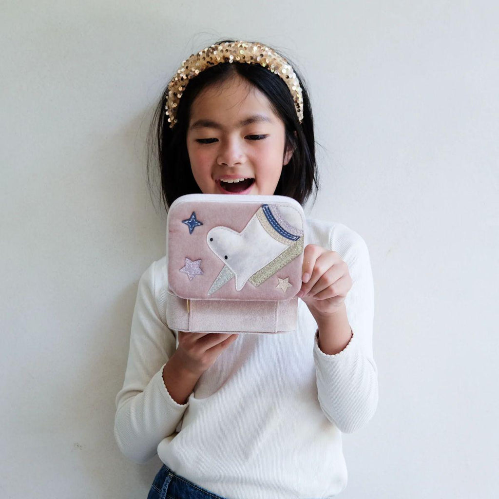 Child holding a pink pouch with a white animal design against a plain background