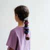 Person with colorful hair ties in a braid on a plain background
