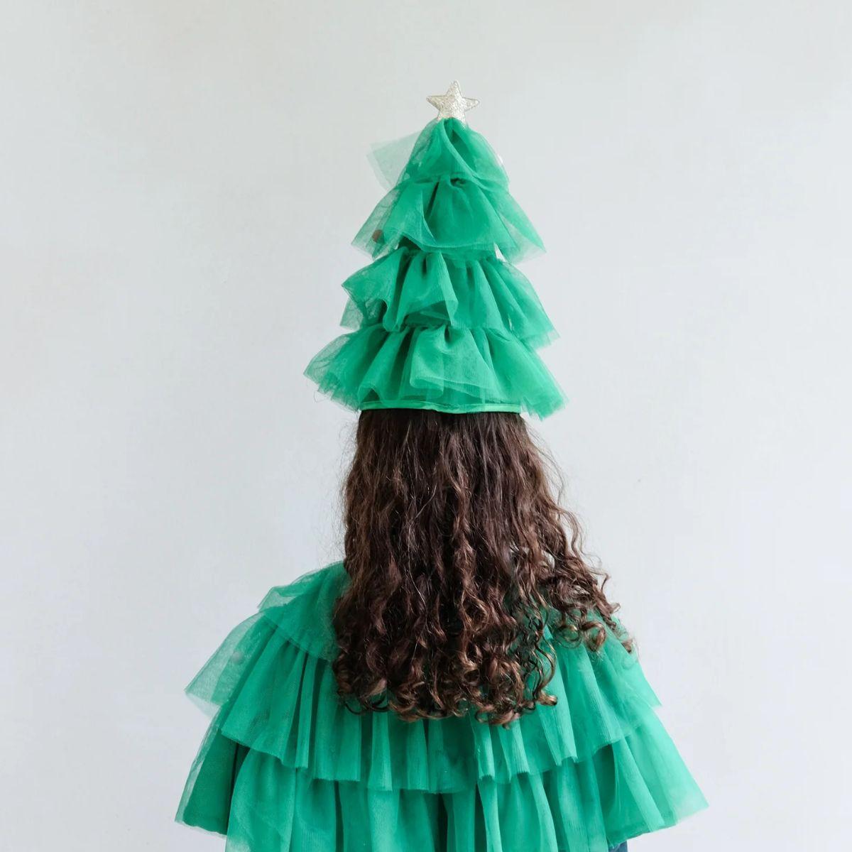 Person wearing a green dress shaped like a Christmas tree with a white background