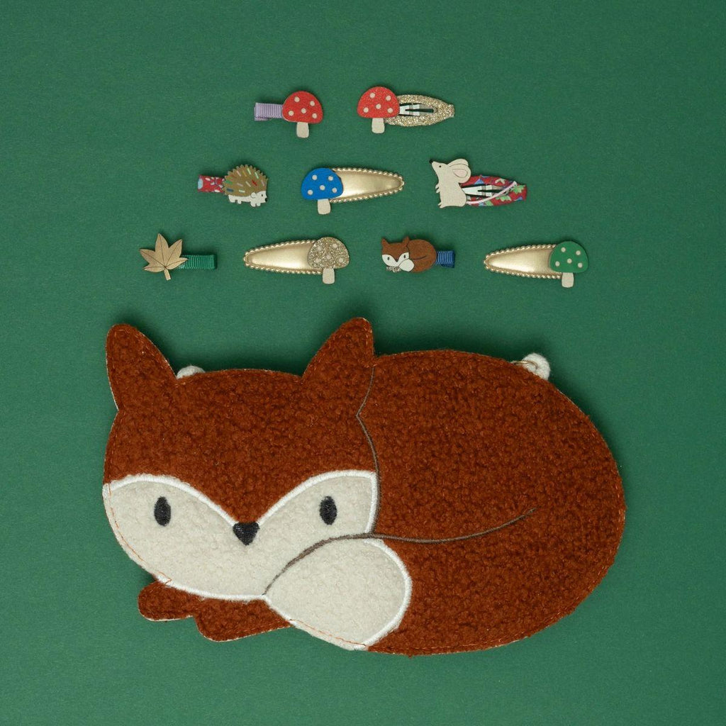 Felt fox patch with various small forest-themed items on a green background