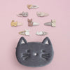 Cat-themed hair clips and pouch on a pink background