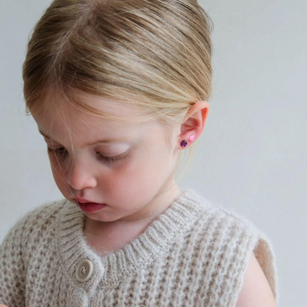 Young girl wearing a beige knitted cardigan with a plain background