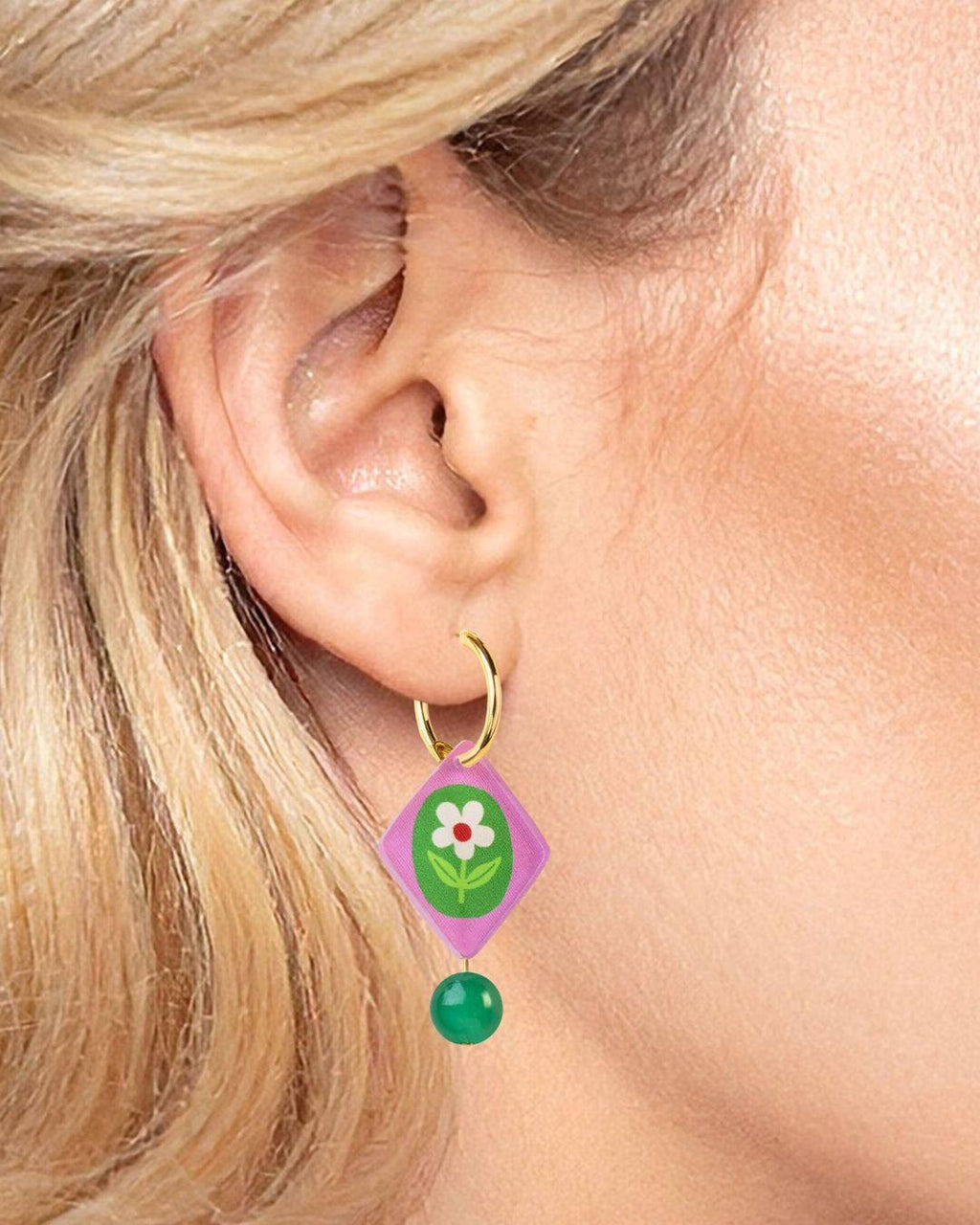 Close-up of a person wearing a colorful earring with a floral design.