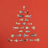 Collection of decorative pins arranged in the shape of a Christmas tree on a red background.