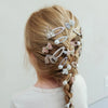 Girl with braided hair adorned with decorative hair clips on a plain background