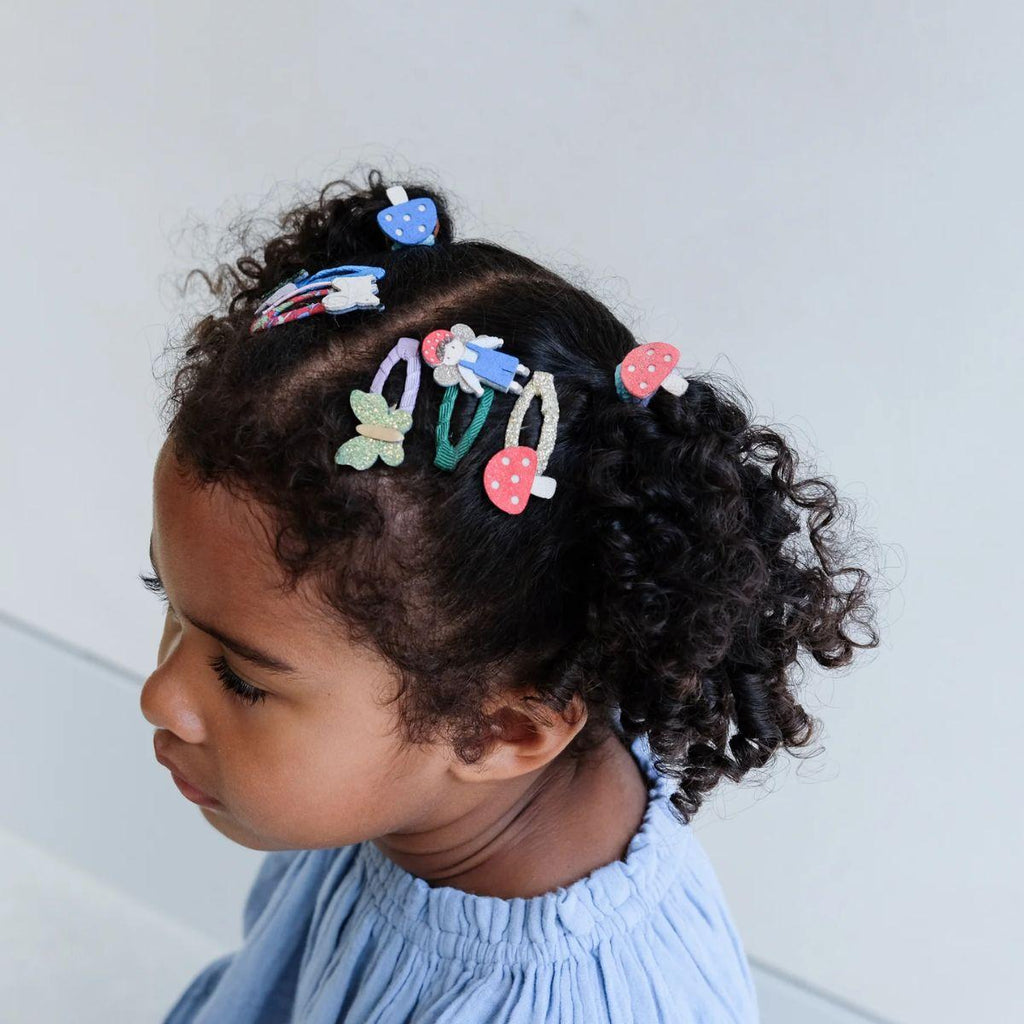 Child with colorful hair clips in curly hair against a light background